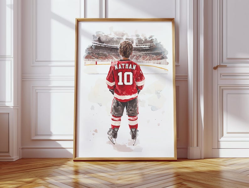 May include: A watercolor painting of a young hockey player wearing a red and white jersey with the name "Nathan" and the number "10" on the back. The player is standing on a snowy ice rink, looking out at a crowd of spectators in the background.