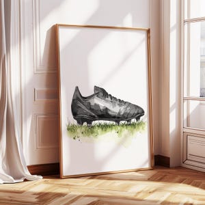 Peut inclure: Une peinture &agrave; l'aquarelle d'un crampon de football noir sur un terrain herbeux vert.