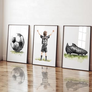 Peut inclure: Trois illustrations &agrave; l'aquarelle dans des cadres noirs. La premi&egrave;re montre un ballon de football noir et blanc. La deuxi&egrave;me montre un gar&ccedil;on portant un maillot de football noir avec le num&eacute;ro 10 et le nom "Nathan" au dos. La troisi&egrave;me montre une chaussure de football noire.
