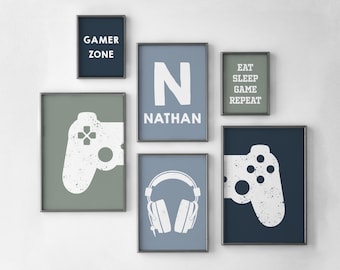 May include: A set of framed wall art with a gaming theme. The art includes a controller graphic, headphones, and text that reads "Gamer Zone", "Eat Sleep Game Repeat", and "N Nathan". The color palette includes shades of blue, green, and white.