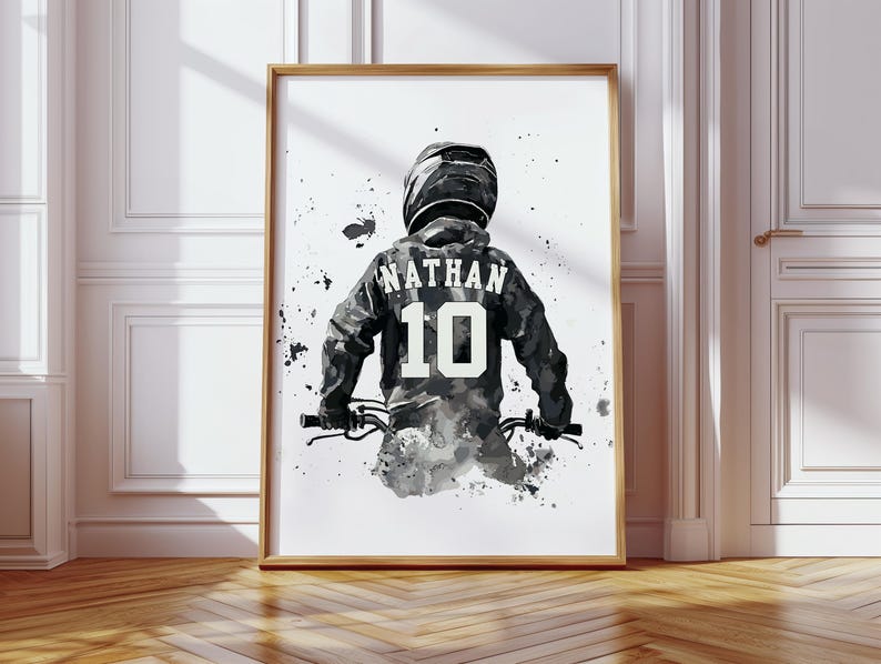 Peut inclure: Impression artistique encadr&eacute;e d'une personne &agrave; v&eacute;lo, portant un casque et un maillot. Le maillot affiche le nom "NATHAN" et le num&eacute;ro "10". L'&oelig;uvre est principalement en noir, blanc et gris, avec des &eacute;claboussures de peinture.