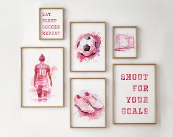Puede incluir: Cinco impresiones de acuarela rosa y blanca con marcos dorados. Las impresiones presentan un balón de fútbol, un jugador de fútbol, una portería, botas de fútbol y el texto "Shoot for your goals".