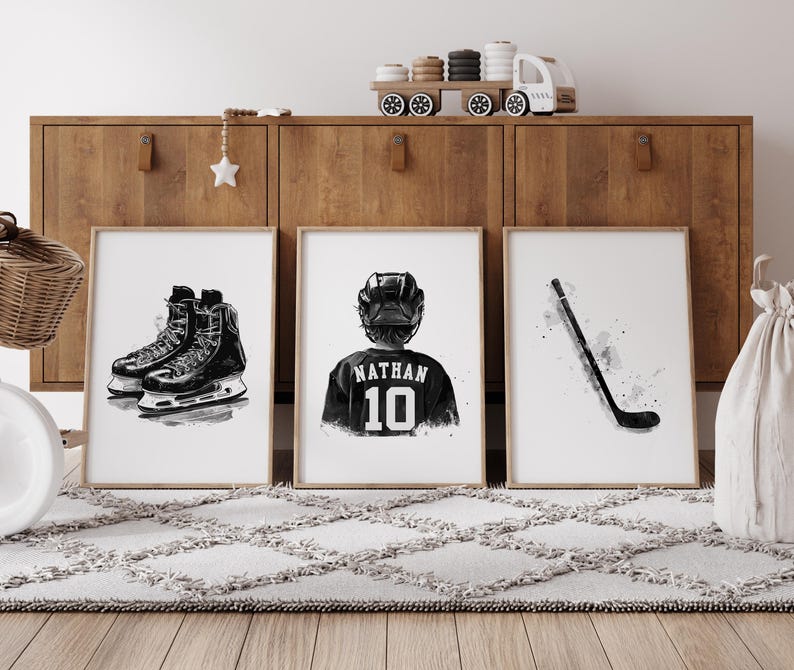 May include: Three black and white illustrations for a hockey themed nursery. The first image shows a pair of hockey skates, the second image shows a hockey player wearing a jersey with the name "Nathan" and the number "10" on the back, and the third image shows a hockey stick.