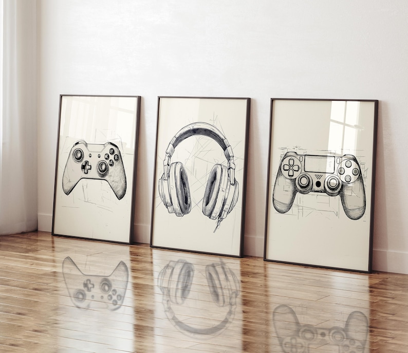 K&ouml;nnte beinhalten: Drei gerahmte Kunstdrucke mit handgezeichneten Skizzen von Gaming-Zubeh&ouml;r. Die Drucke zeigen einen Gamecontroller, Kopfh&ouml;rer und einen weiteren Gamecontroller. Die Kunstwerke sind in Schwarzwei&szlig; gehalten, vor einem cremefarbenen Hintergrund und in Schwarz gerahmt.
