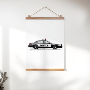 May include: Black and white police car illustration with the word "POLICE" on the side. The car has a red light on top and is hanging from a wooden frame. The artwork is displayed on a white wall.