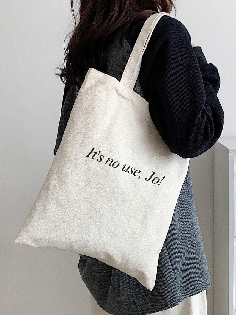 Pode incluir: Uma bolsa tote de lona branca com texto preto que diz "It's no use, Jo!"