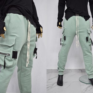 May include: Light green cargo pants with black straps and a white drawstring. The pants have reflective silver stripes on the sides.