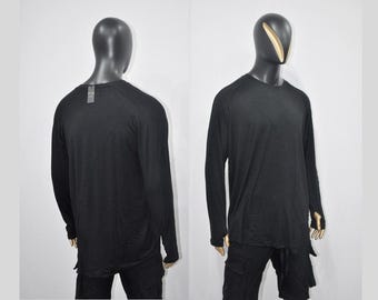 May include: Black long-sleeved shirt with a round neckline and a slightly longer back hem. The shirt has a relaxed fit and features a unique design with a slight asymmetry at the hem.