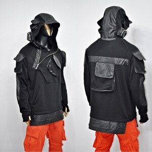 May include: Black hooded sweatshirt with a zipper closure, multiple pockets, and a layered design. The sweatshirt has a black and silver mask attached to the hood.