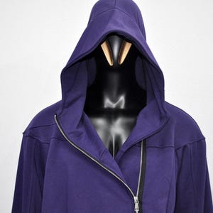 Puede incluir: Una sudadera con capucha de color p&uacute;rpura oscuro con una cremallera plateada de largo completo. La sudadera se muestra en un maniqu&iacute; negro. El fondo es una pared blanca lisa.