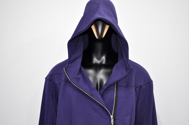 Puede incluir: Una sudadera con capucha de color p&uacute;rpura oscuro con una cremallera plateada de largo completo. La sudadera se muestra en un maniqu&iacute; negro. El fondo es una pared blanca lisa.