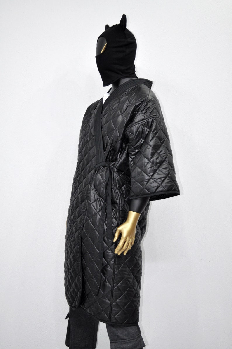 May include: A black quilted robe with a long sleeve and a tie belt. The robe is made of a soft, comfortable material and has a diamond pattern.