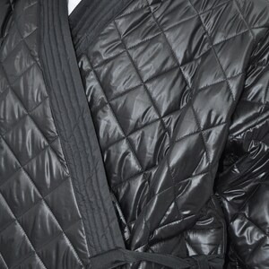 May include: A black quilted robe with a long sash tie. The robe has a diamond pattern and a satin-like sheen.