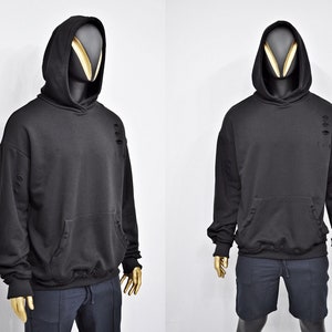 Peut inclure: Sweat-shirt à capuche noir avec des détails usés et une poche kangourou. Le sweat-shirt est présenté sur un mannequin.