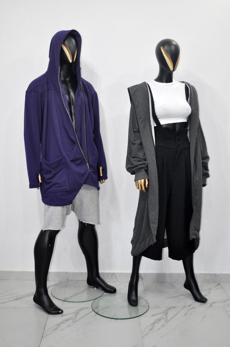 Puede incluir: Dos maniqu&iacute;es exhiben atuendos contempor&aacute;neos. Uno lleva una chaqueta con capucha morada con cremallera y pantalones cortos grises. El otro maniqu&iacute; viste un top corto blanco, pantalones negros de cintura alta con tirantes y una rebeca larga gris.