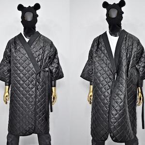 May include: Black quilted robe with a long, wrap-around design and a tie closure. The robe has a diamond-shaped quilted pattern and is made of a soft, comfortable fabric.