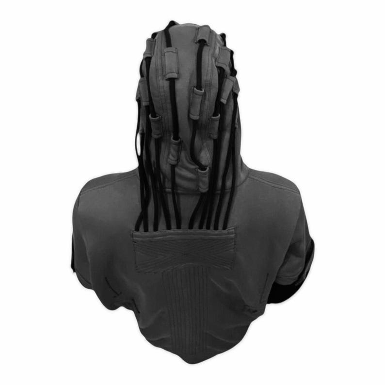 K&ouml;nnte beinhalten: Ein grauer Kapuzenpullover mit einem einzigartigen Design, das mehrere schwarze Kordeln aufweist, die aus der Kapuze herausragen. Die R&uuml;ckseite des Kapuzenpullovers hat ein strukturiertes Panel und einen rechteckigen Aufn&auml;her. Die &Auml;rmel haben schwarze Akzente.