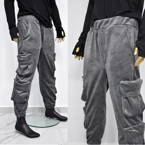 Puede incluir: Pantalón cargo gris con múltiples bolsillos. El pantalón tiene un corte holgado y una cintura con cordón.
