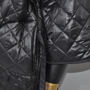 May include: Black quilted jacket with a diamond pattern. The jacket has a zipper closure and a stand-up collar.