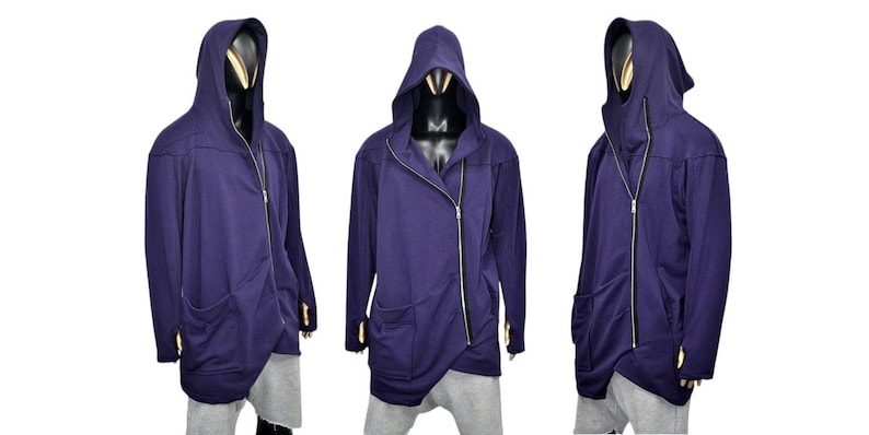 Puede incluir: Chaqueta con capucha azul oscuro con cierre de cremallera diagonal y dos bolsillos delanteros. La chaqueta tiene un dise&ntilde;o asim&eacute;trico &uacute;nico y se muestra en un maniqu&iacute;. La chaqueta es larga y tiene agujeros para los pulgares.