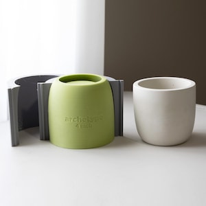 Könnte beinhalten: Eine hellgrüne 10 cm Archetype Pflanzform mit einer grauen Stützstruktur und einem weißen Pflanzgefäß. Die Form ist zylindrisch mit abgerundeten Kanten. Das weiße Pflanzgefäß ist ebenfalls zylindrisch mit abgerundeten Kanten.