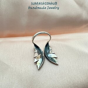 Puede incluir: Anillo de plata con dise&ntilde;o de alas. Las alas est&aacute;n abiertas y tienen una superficie texturizada. El anillo est&aacute; hecho a mano.