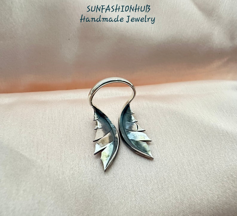 Puede incluir: Anillo de plata con dise&ntilde;o de alas. Las alas est&aacute;n abiertas y tienen una superficie texturizada. El anillo est&aacute; hecho a mano.