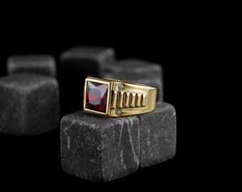 May include: A gold ring with a square red gemstone and two small white gemstones on the band.