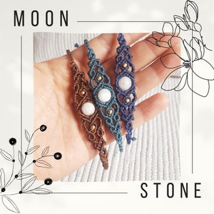 Op de afbeelding: Drie macramé armbanden met witte maansteen kralen. De armbanden zijn bruin, blauw en donkerblauw. De armbanden zijn aan elkaar gebonden en worden in een hand gehouden.