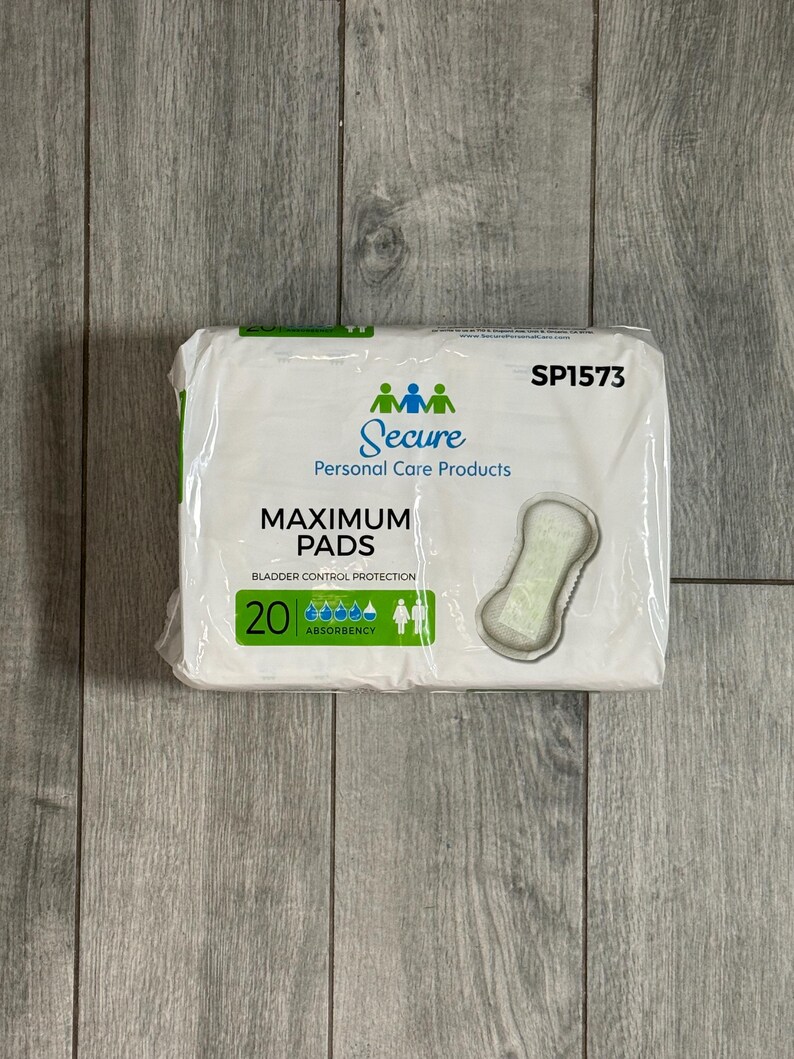 May include: A packet of Secure Maximum Pads for bladder control protection. The white packet features the brand name and product details in blue and green. The packet contains 20 pads and has an image of a pad on the front.