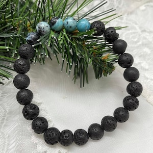May include: A black lava rock bracelet with blue and black gemstone beads.