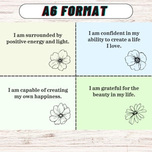 May include: Four affirmation cards with floral illustrations. The cards are light green, light blue, and yellow. The text on the cards reads: "I am surrounded by positive energy and light." "I am confident in my ability to create a life I love." "I am capable of creating my own happiness." "I am grateful for the beauty in my life."