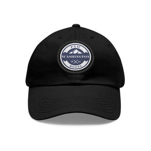 May include: Black baseball cap with a circular patch featuring the text "PNW WASHINGTON ROOTS 1967" in white and navy blue. The patch includes a mountain graphic and crossed axes.