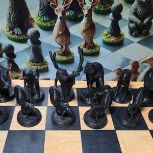 K&ouml;nnte beinhalten: Ein einzigartiges Schachspiel mit Tierfiguren. Die schwarzen Figuren sind tiefschwarz, w&auml;hrend die wei&szlig;en Figuren verschiedene Farben haben. Das Brett hat ein klassisches schwarz-braunes Schachmuster. Die Figuren umfassen Hirsche, B&auml;ren und andere Wildtiere.