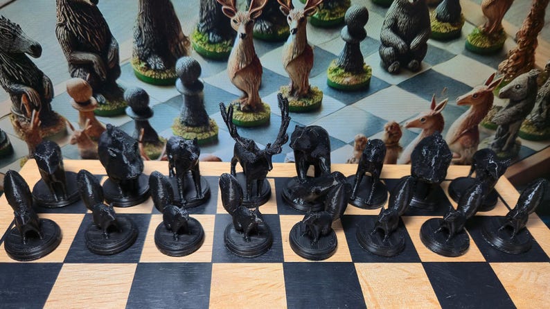 K&ouml;nnte beinhalten: Ein einzigartiges Schachspiel mit Tierfiguren. Die schwarzen Figuren sind tiefschwarz, w&auml;hrend die wei&szlig;en Figuren verschiedene Farben haben. Das Brett hat ein klassisches schwarz-braunes Schachmuster. Die Figuren umfassen Hirsche, B&auml;ren und andere Wildtiere.