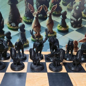 K&ouml;nnte beinhalten: Ein einzigartiges Schachspiel mit Tierfiguren. Die schwarzen Figuren sind stilisiert, w&auml;hrend die gegnerischen Figuren braun und hellbraun sind und verschiedene Tiere wie Hirsche, B&auml;ren und Pferde darstellen. Das Schachbrett hat ein klassisches schwarz-braunes Schachmuster.