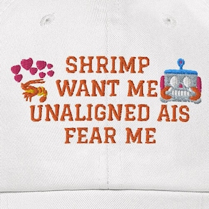 May include: White baseball cap with orange embroidered text that reads "Shrimp Want Me Unaligned AIs Fear Me". The text is surrounded by a pink heart design and a cartoon shrimp and robot.