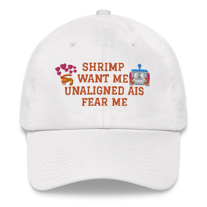 Peut inclure: Casquette de baseball blanche avec un texte brod&eacute; orange qui dit "Shrimp Want Me Unaligned AIs Fear Me". Le texte est entour&eacute; d'un motif de c&oelig;ur rose et d'une crevette et d'un robot de dessin anim&eacute;.