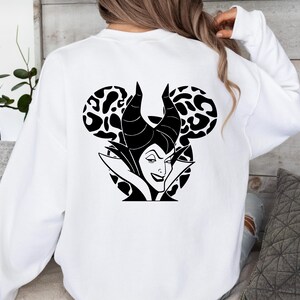May include: White sweatshirt with a black and white graphic of a Disney villain. The design features the character's face, horns, and a Mickey Mouse ear shape with a leopard print pattern.