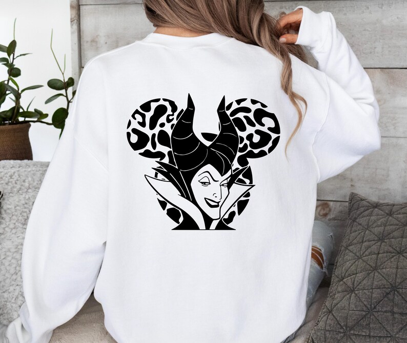 May include: White sweatshirt with a black and white graphic of a Disney villain. The design features the character's face, horns, and a Mickey Mouse ear shape with a leopard print pattern.