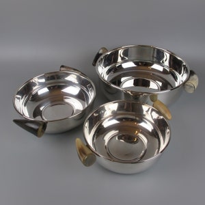 May include: Three silver bowls with horn handles. The bowls are nested inside each other, with the largest bowl at the top and the smallest bowl at the bottom.