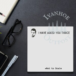 May include: White notepad with a black and white illustration of a man's face and the text "I have asked you thrice Outpost Ivanhoe *Not to Scale".