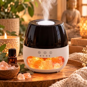 May include: A black and white electric essential oil diffuser with a transparent lower section containing glowing orange salt rocks. The device features a white control panel with icons for a timer, power, and light, along with settings for ON, 1H, 3H, and 6H.