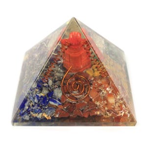 Op de afbeelding: Een heldere kristallen piramide met een koperen draadspiraal en verschillende gekleurde kristallen erin, waaronder rood, oranje, geel, blauw en wit.