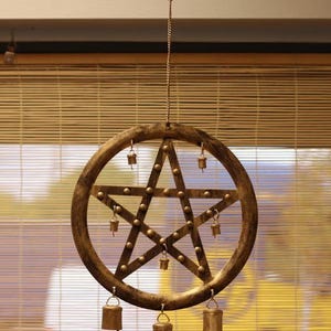 Peut inclure: Carillon en métal doré de style rustique, orné d'un pentagramme. L'étoile est entourée d'un cercle et ornée de petites cloches. Le carillon est suspendu à une chaîne et à une tige de bambou.