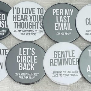 Op de afbeelding: Een verzameling van acht ronde buttons met humoristische zinnen in witte tekst op grijze en witte achtergronden. Zinnen zijn onder meer "As Stated Previously" en "Thanks in Advance".