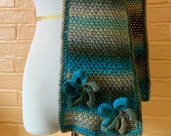 Bufanda de punto musgo tejida a mano con apliques florales en tonos tostados, verde oliva y turquesa.