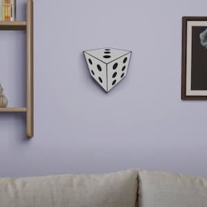 May include: A white 3D optical illusion die with black dots on each side. The die is mounted on a wall.