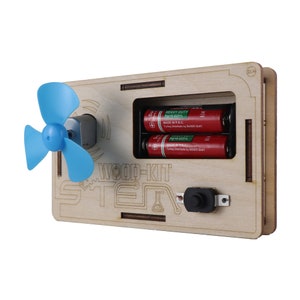 Op de afbeelding: Een houten kit voor het bouwen van een STEM-project. De kit bevat een kleine ventilator, een motor, een schakelaar en twee batterijen. De kit is gelabeld "WOOD-KIT STEM".
