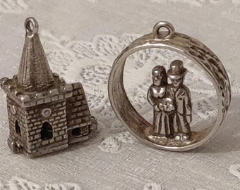 May include: Two silver charm pendants, one shaped like a church and the other a circle with a bride and groom inside.